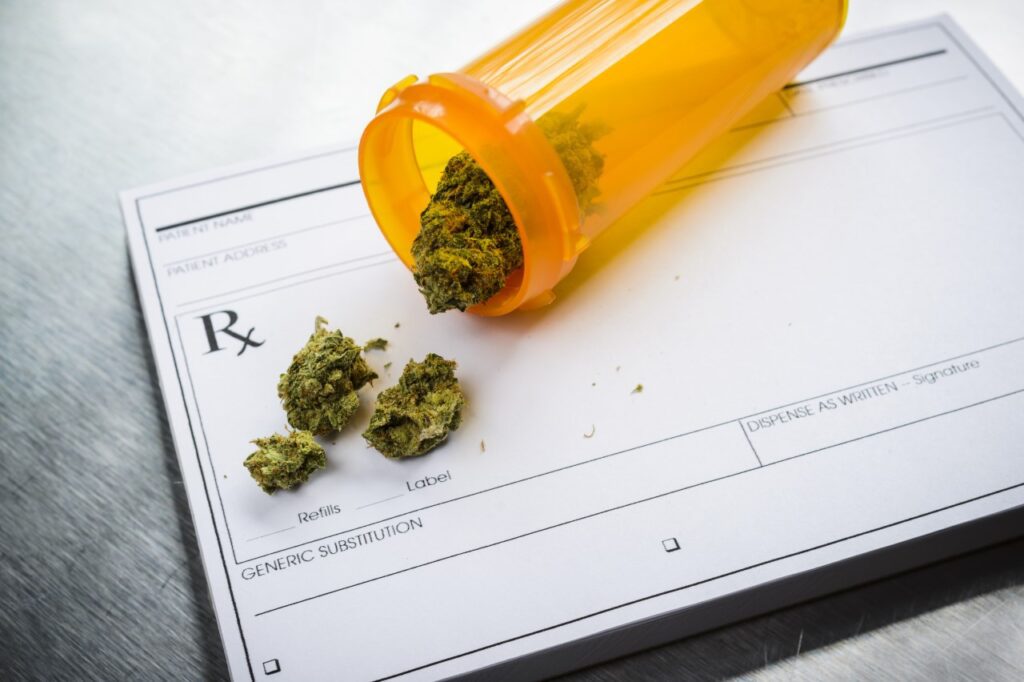 Prescription pad with cannabis buds spilling from an orange pill bottle.